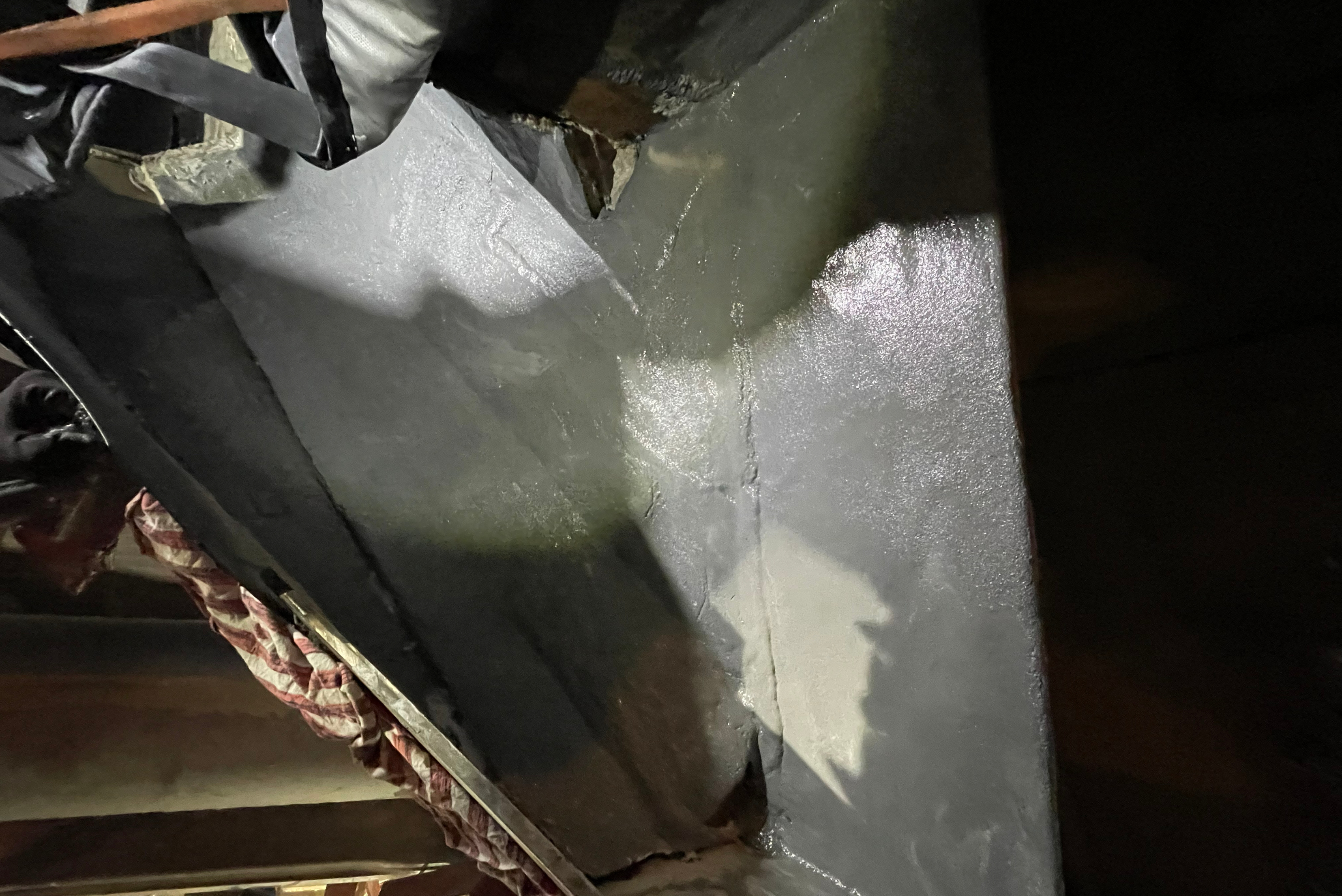 Vue rapprochée de l'intérieur d'une trémie métallique sombre avec des surfaces revêtues.