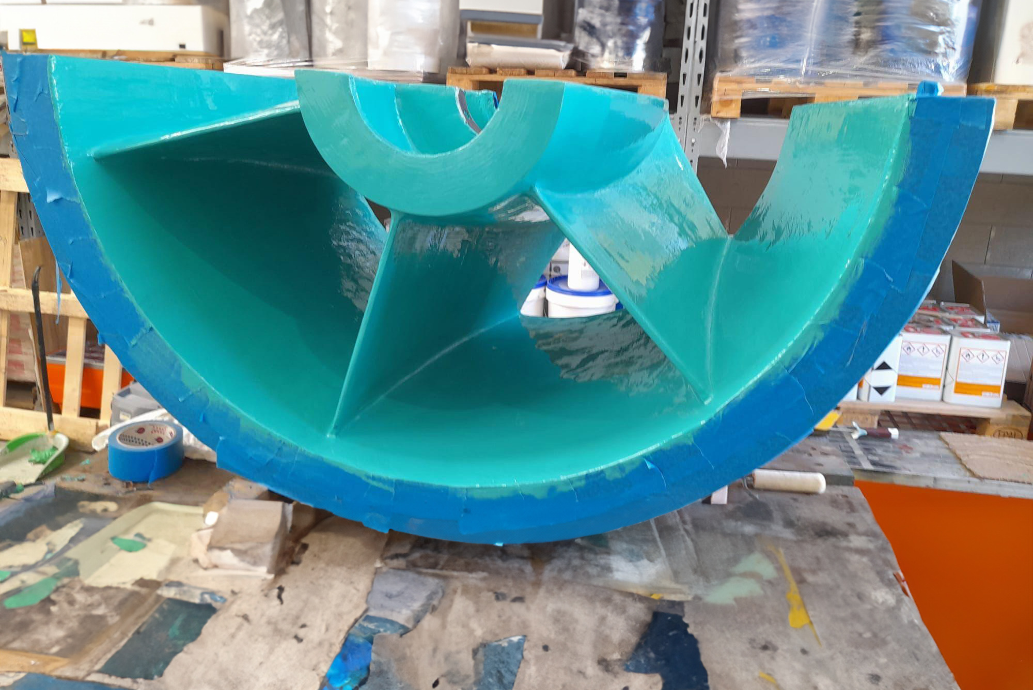 Vue de face d'un composant industriel semi-circulaire doté de pales intérieures, entièrement enduit d'un revêtement protecteur brillant de couleur turquoise et bleue